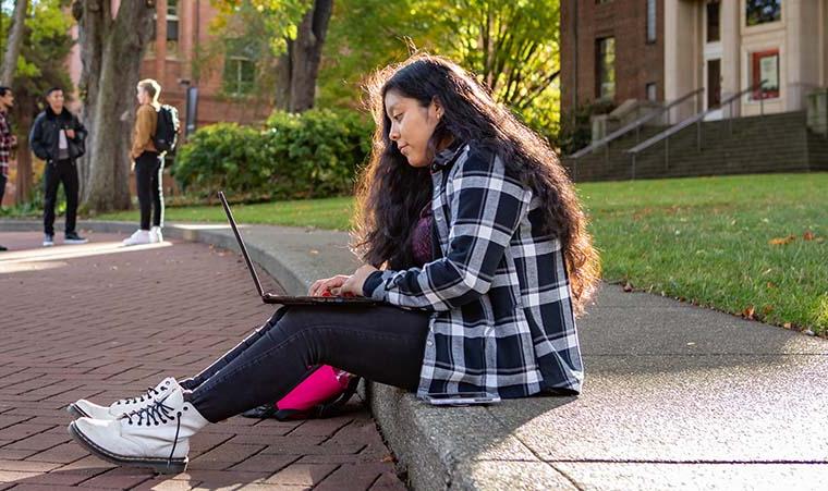An SPU student works on their laptop in Tiffany Loop